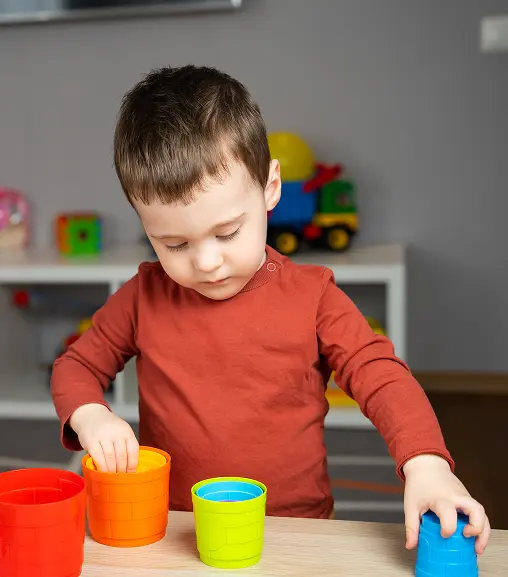 young boy playing with cups